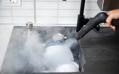 Evin dezenfeksiyon ve dezenfekte edilmesi, mutfak lavabosundaki buharlı bulaşıklar.