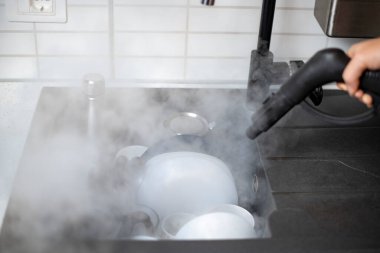 Evin dezenfeksiyon ve dezenfekte edilmesi, mutfak lavabosundaki buharlı bulaşıklar.
