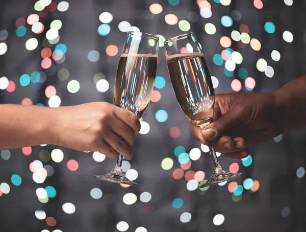 Bir kız ve bir erkek, güzel bir şenlik arka planında şampanya kadehleriyle çiftleşirler, koyu bir arka planda odak ışıklarının dışında kalan siyahlardan oluşurlar.