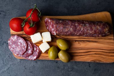 Sosisli, peynirli, zeytinli, domatesli, koyu gri çimento arka planda.