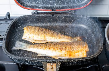 Siyah ızgarada pişmiş iki levrek balığı.