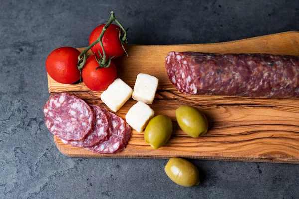 Sosisli, peynirli, zeytinli, domatesli, koyu gri çimento arka planda.