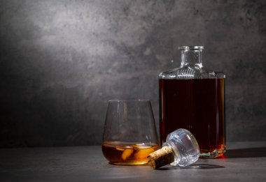 Kare viski şişesi ve buzlu koyu gri çimento arka plan.