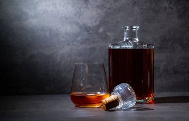 Kare viski şişesi ve buzlu koyu gri çimento arka plan.