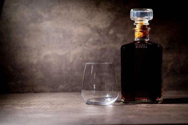 Eine Flasche Whiskey Quadratischer Form Lichtstrahl Neben Einem Leeren Glas — Stockfoto