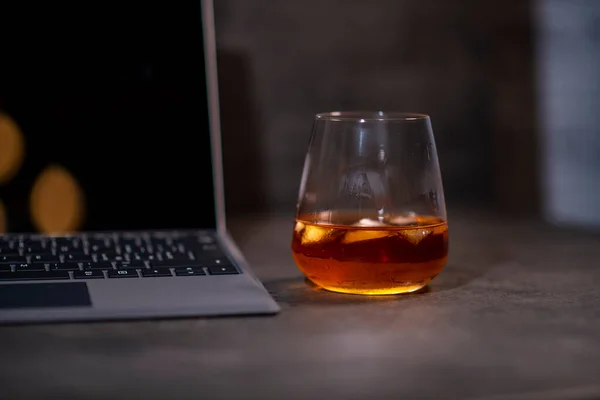 Whiskey Glas Mit Eis Der Hand Neben Laptop Auf Dunkelgrauem — Stockfoto