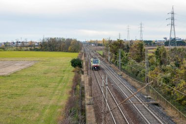 Lokomotif arazide rayların üzerinde gidiyor.
