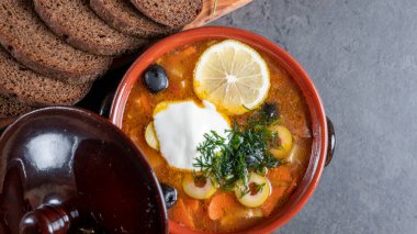 Kil tabakta limon ve ekşi krema, tuz, biber ve çavdar ekmeği ve gri çimento arka planda.