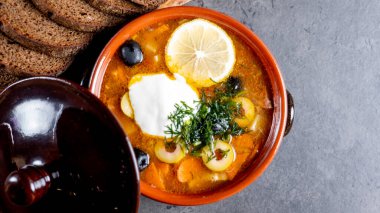 Kil tabakta limon ve ekşi krema, tuz, biber ve çavdar ekmeği ve gri çimento arka planda.