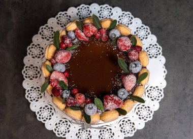 tiramisu çikolata jöleli ve koyu gri arka planda böğürtlenlerle süslenmiş.