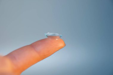 Işık arkaplanındaki parmakta kontakt lens