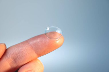 Işık arkaplanındaki parmakta kontakt lens