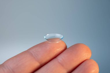 Işık arkaplanındaki parmakta kontakt lens