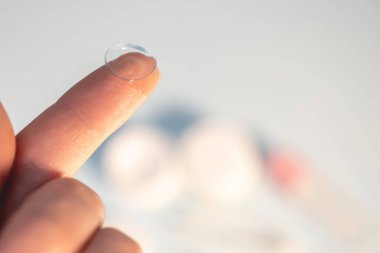 Işık arkaplanındaki parmakta kontakt lens