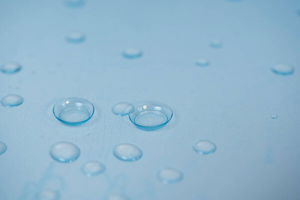 contact lenses on blue background with water drops