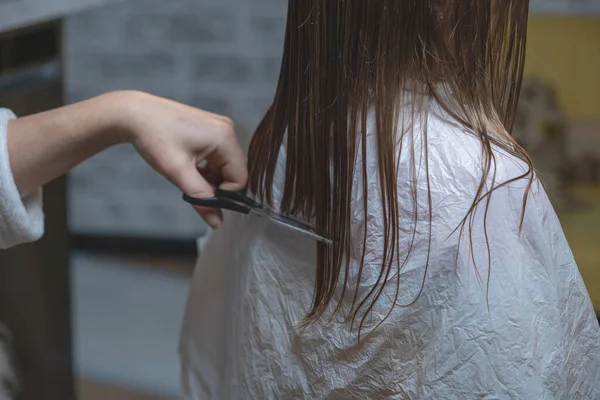 hair cutting at home, mom cuts daughter\'s hair in the kitchen