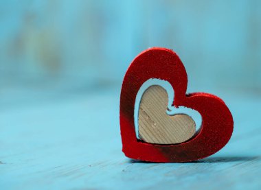 iki ahşap kalp, biri kırmızıya boyanmış diğeri mavi arka planda ahşap.