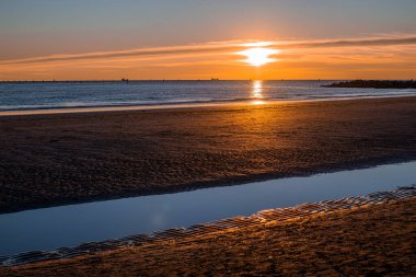 Denizde gün batımı, deniz ve yoldan geçenlerle aynı seviyede güneş.