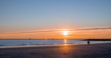 Denizde gün batımı, deniz ve yoldan geçenlerle aynı seviyede güneş.