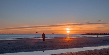 Denizde gün batımı, deniz ve yoldan geçenlerle aynı seviyede güneş.