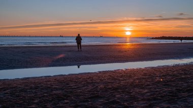 Denizde gün batımı, deniz ve yoldan geçenlerle aynı seviyede güneş.