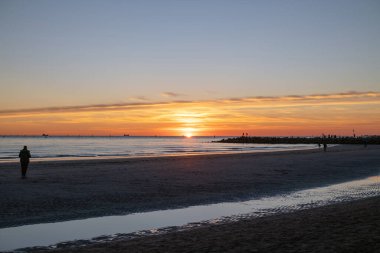 Denizde gün batımı, deniz ve yoldan geçenlerle aynı seviyede güneş.
