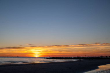 Denizde gün batımı, deniz ve yoldan geçenlerle aynı seviyede güneş.