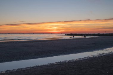 Denizde gün batımı, deniz ve yoldan geçenlerle aynı seviyede güneş.