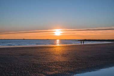 Denizde gün batımı, deniz ve yoldan geçenlerle aynı seviyede güneş.