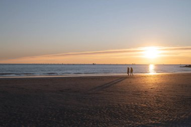 Denizde gün batımı, deniz ve yoldan geçenlerle aynı seviyede güneş.