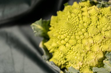 Koyu yeşil kumaş ve sağlıklı yiyecek üzerine Romanesco brokoli.