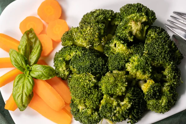 Zdrowa Żywność Gotowane Brokuły Marchew Liść Bazalny Białym Talerzu Ciemnozielonej — Zdjęcie stockowe