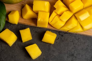 Olgun mango koyu gri arka planda küp şeklinde kesilmiş.