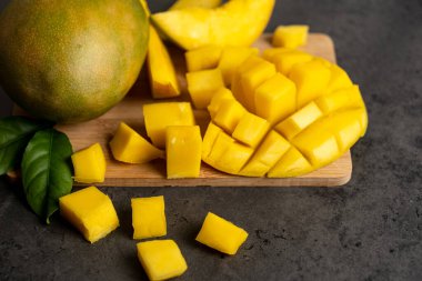 Olgun mango koyu gri arka planda küp şeklinde kesilmiş.