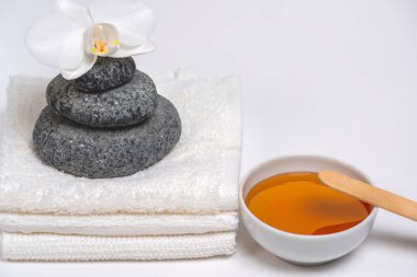 Spa stili, beyaz havlular, bal kabı, Zen taşları, orkide: rahatlatıcı masaj için her şey.