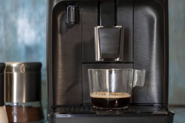 Kahve makinesi mavi ahşap arka planda espresso yapıyor.