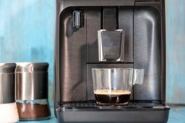 Kahve makinesi mavi ahşap arka planda espresso yapıyor.