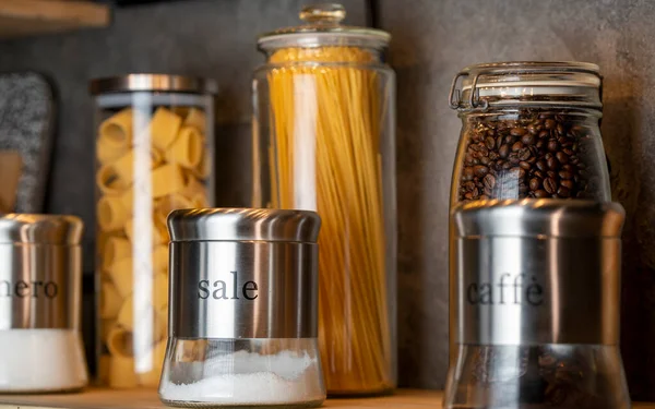 pasta, spaghetti, sugar, salt and coffee in different containers on the shelf