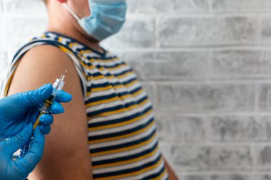 Sağlık görevlileri bir adama koronavirüs aşısı yapar.