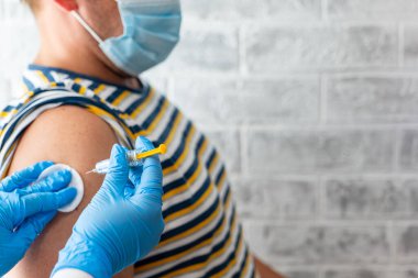 Sağlık görevlileri bir adama koronavirüs aşısı yapar.