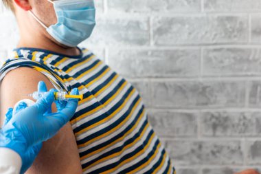 Sağlık görevlileri bir adama koronavirüs aşısı yapar.