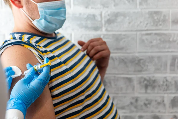 Sağlık görevlileri bir adama koronavirüs aşısı yapar.