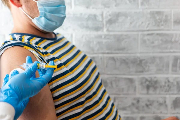 Sağlık görevlileri bir adama koronavirüs aşısı yapar.