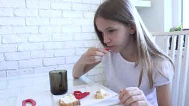 Çocuk mutfakta kahvaltı yapıyor, kız sebze yiyor, aç sarışın çocuk biberin tadını çıkarıyor, sağlıklı yemekler, çocuk sağlığı hizmetleri.