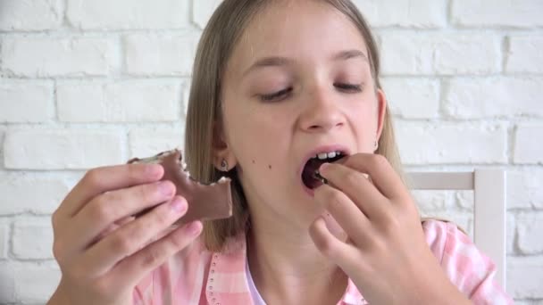 Gyerek csokoládét eszik a konyhában, Gyerek édességet eszik reggelinél, Lány kóstoló finomságok otthon — Stock videók