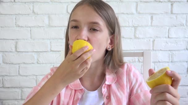 Kind isst Zitrone, Kind frisst Früchte, junges Mädchen beim Frühstück in der Küche — Stockvideo