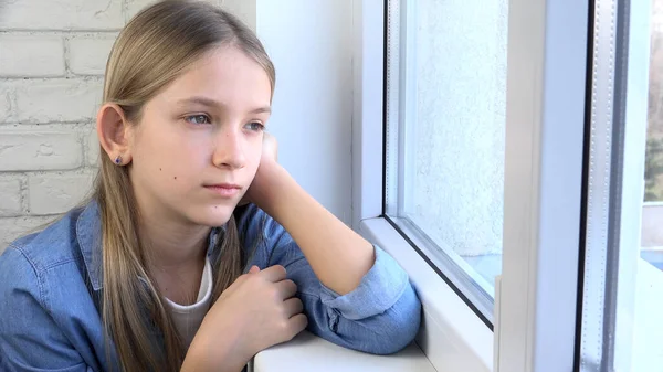 悲しい子供窓を見ます 不幸な子供 退屈思考の女の子 ティーンエイジャーの顔 コロナウイルス危機の自宅で隔離された人々 ストック画像