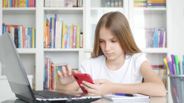 Παιδί που χρησιμοποιεί Smartphone Μελετώντας σε Video Conferencing, Παιδική Εκπαίδευση, Γράφοντας στη Βιβλιοθήκη, Schoolgirl Συνομιλία, Online Εκπαίδευση — Αρχείο Βίντεο