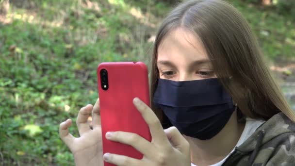 Sick Girl with Protective Mask due Coronavirus Pandemic, Παιδική περιήγηση στο διαδίκτυο στο Smartphone στο Πάρκο, Παιδικό παιχνίδι Smart Phone — Αρχείο Βίντεο