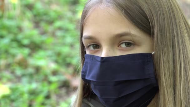 Больной ребенок в защитной маске из-за пандемии коронавируса, грустная девочка, изолированная в парке, скучающий несчастный подросток, не играющий — стоковое видео